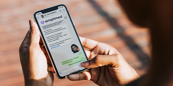 Celular com mensagem automática de confirmação de consulta por WhatsApp da Amplimed.