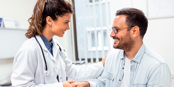 Médica e paciente conversando, com aparência feliz, simbolizando a adesão aos tratamentos.