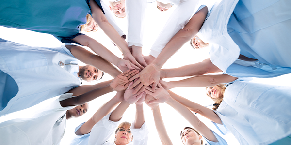 Equipe para clínica médica com mãos à frente, uma em cima da outra..