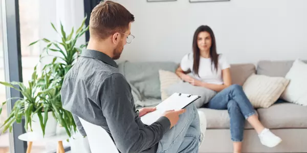 Psicólogo anotando queixas da paciente em ficha de anamnese