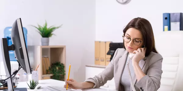 Recepcionista em serviços de saúde atendendo telefone.